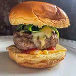 Homemade lamb burger in a bun on a white plate