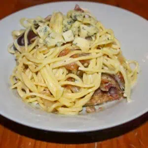 Parma ham fig and blue cheese spaghetti In a white bowl on a wooden table