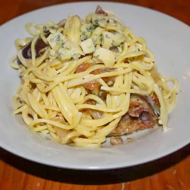 Parma ham fig and blue cheese spaghetti In a white bowl on a wooden table