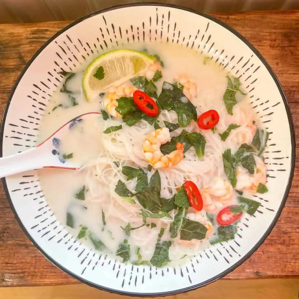 Steaming Tom Kha soup in a white ceramic bowl