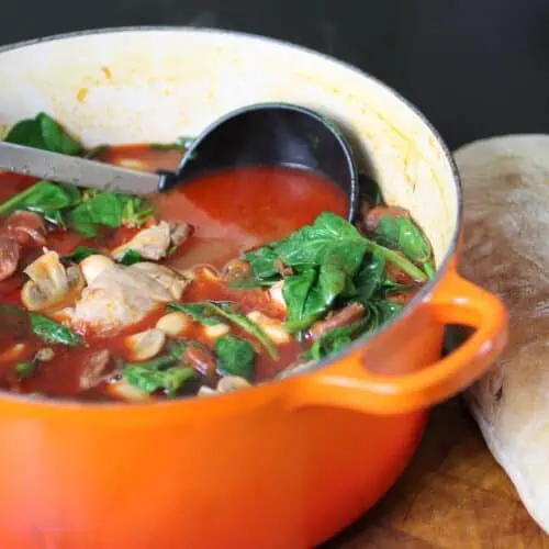 rustic chicken and chorizo stew with butter beans served in a deep bowl with crusty bread on the side