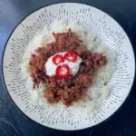 4 hour slow cooked beef chilli con carne topped with soured cream and red chillies