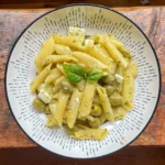 pesto pasta with feta and olives in a white bowl