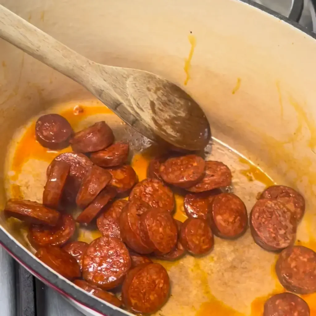 sliced chorizo frying in a pan, paprika oil pooling