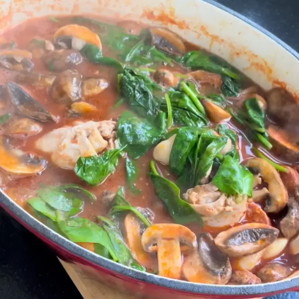 fresh spinach wilting into hot chicken and chorizo stew