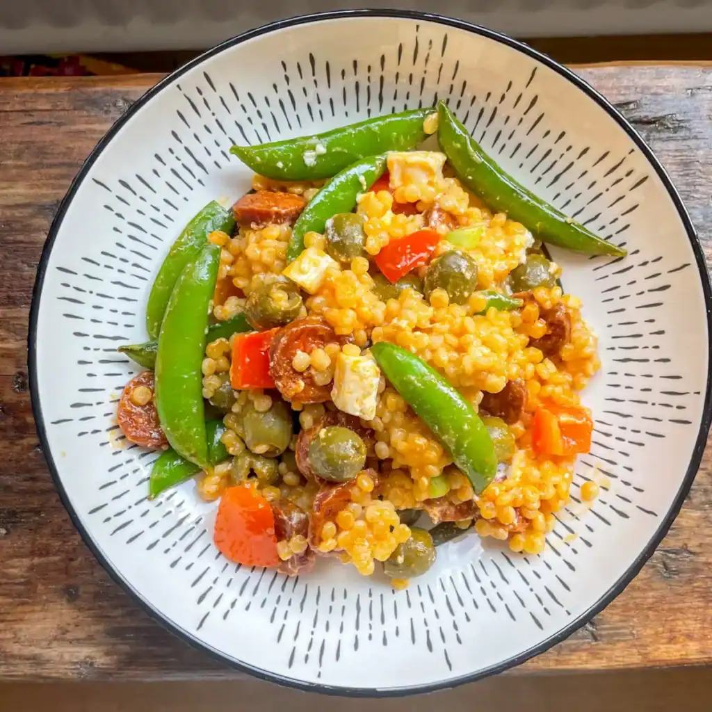 Giant couscous salad with spicy chorizo, crumbled feta, snap peas, and olives – easy and flavour-packed homemade lunch or side.