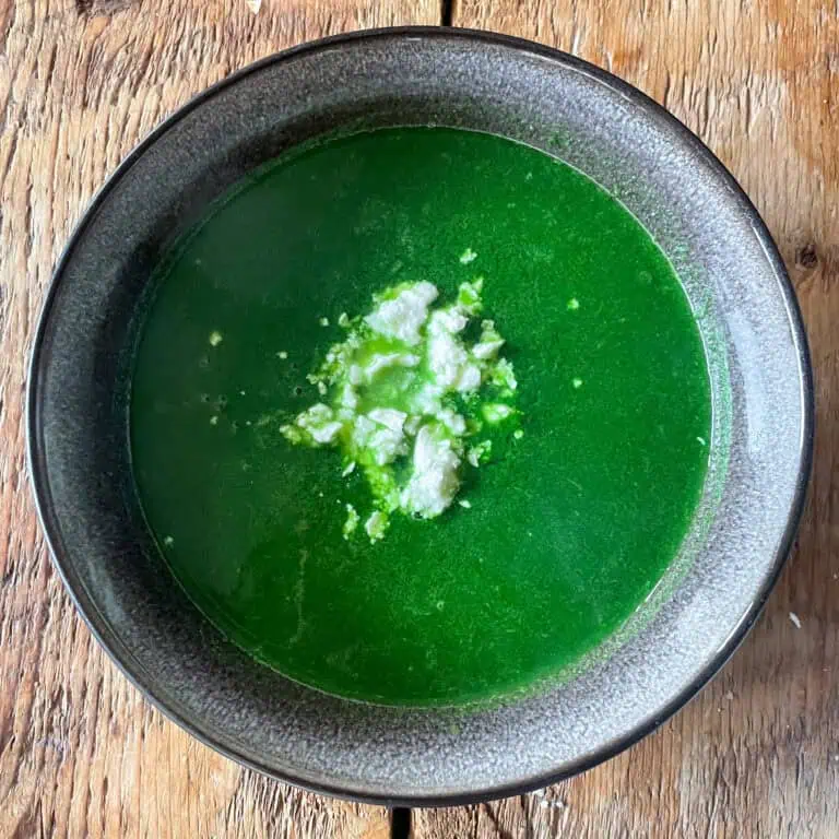 Smooth spinach soup garnished with fresh herbs