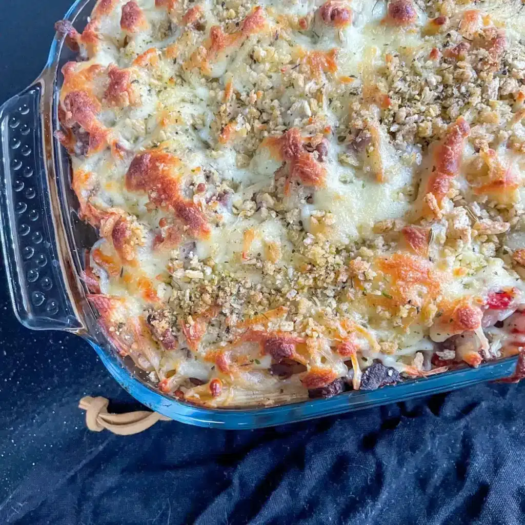 Close up of bolognese pasta bake in an oven dish with a cheesy topping