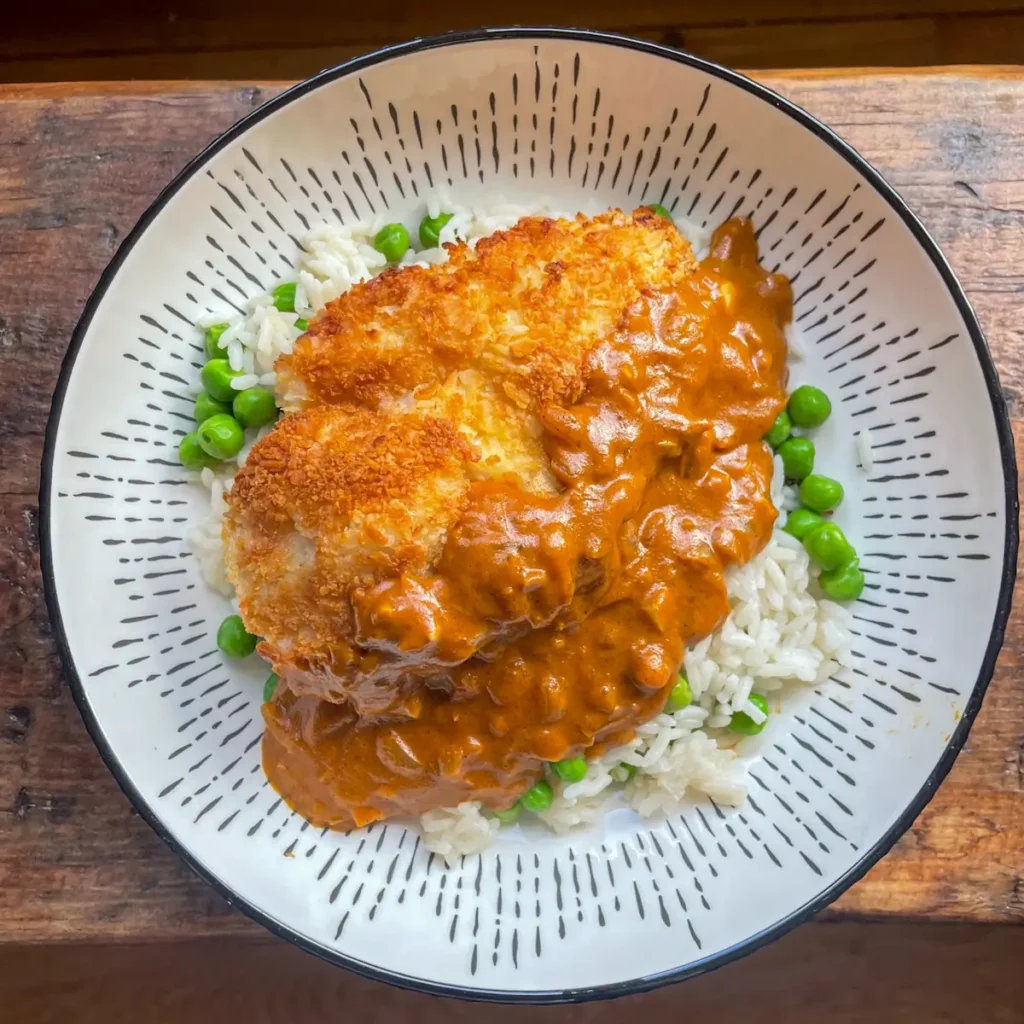 Chicken katsu curry hero shot from above on a bed of rice and peas in a white bowl