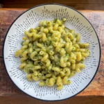 overhead shot of cheesy pesto and spinach pasta in a white bowl