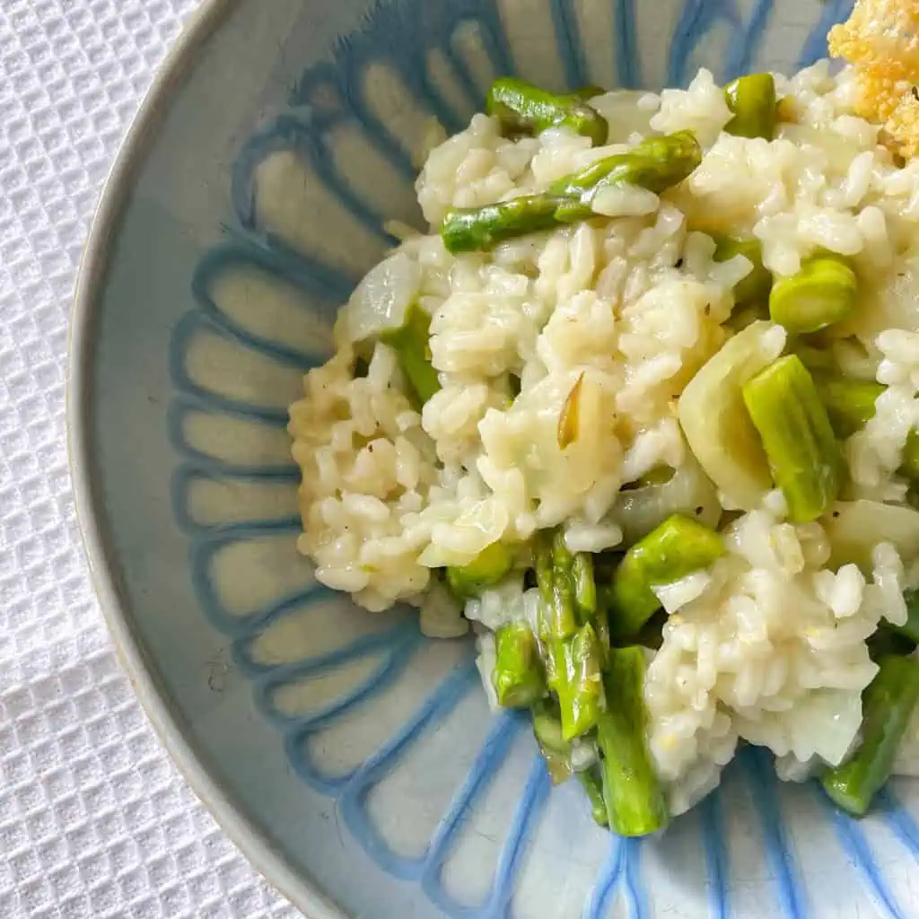 Close up of homemade risotto with fresh green asparagus, topped with Parmesan crisp
