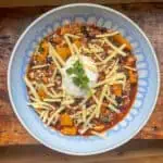 One pot Mexican bean stew in a blue bowl with cheese on top