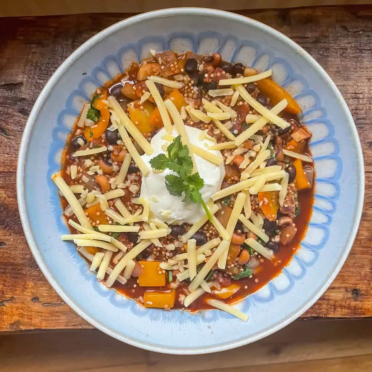 One pot Mexican bean stew in a blue bowl with cheese on top