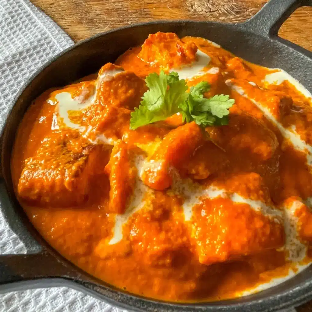 Butter halloumi curry in a black cast iron dish, topped with coriander
