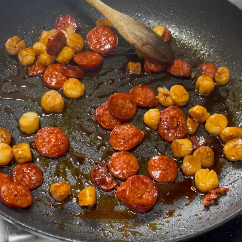 Process shot 2: chorizo and scallops cooking in a frying pan