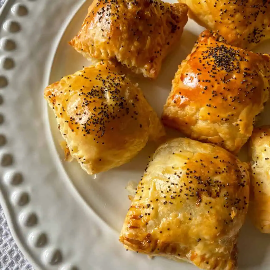 Golden puff pastry smoked cheese sausage rolls topped with poppy seeds