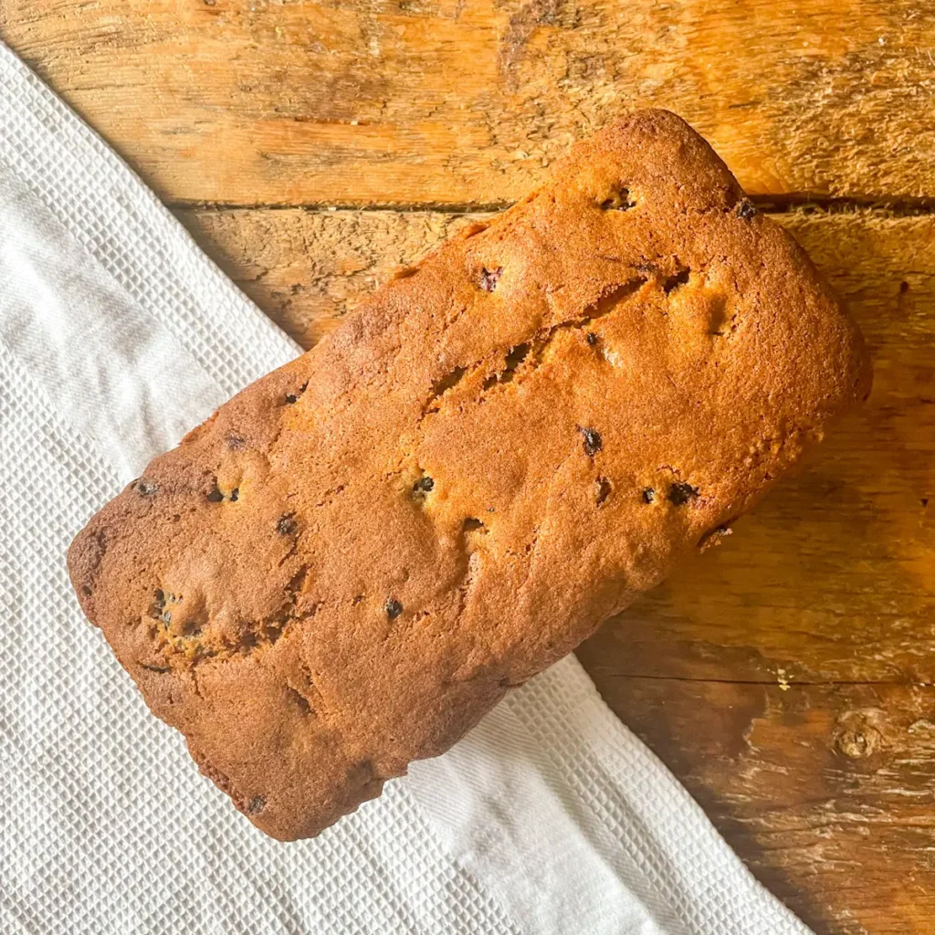 Top view of a golden brown blackberry loaf cake on a wooden board