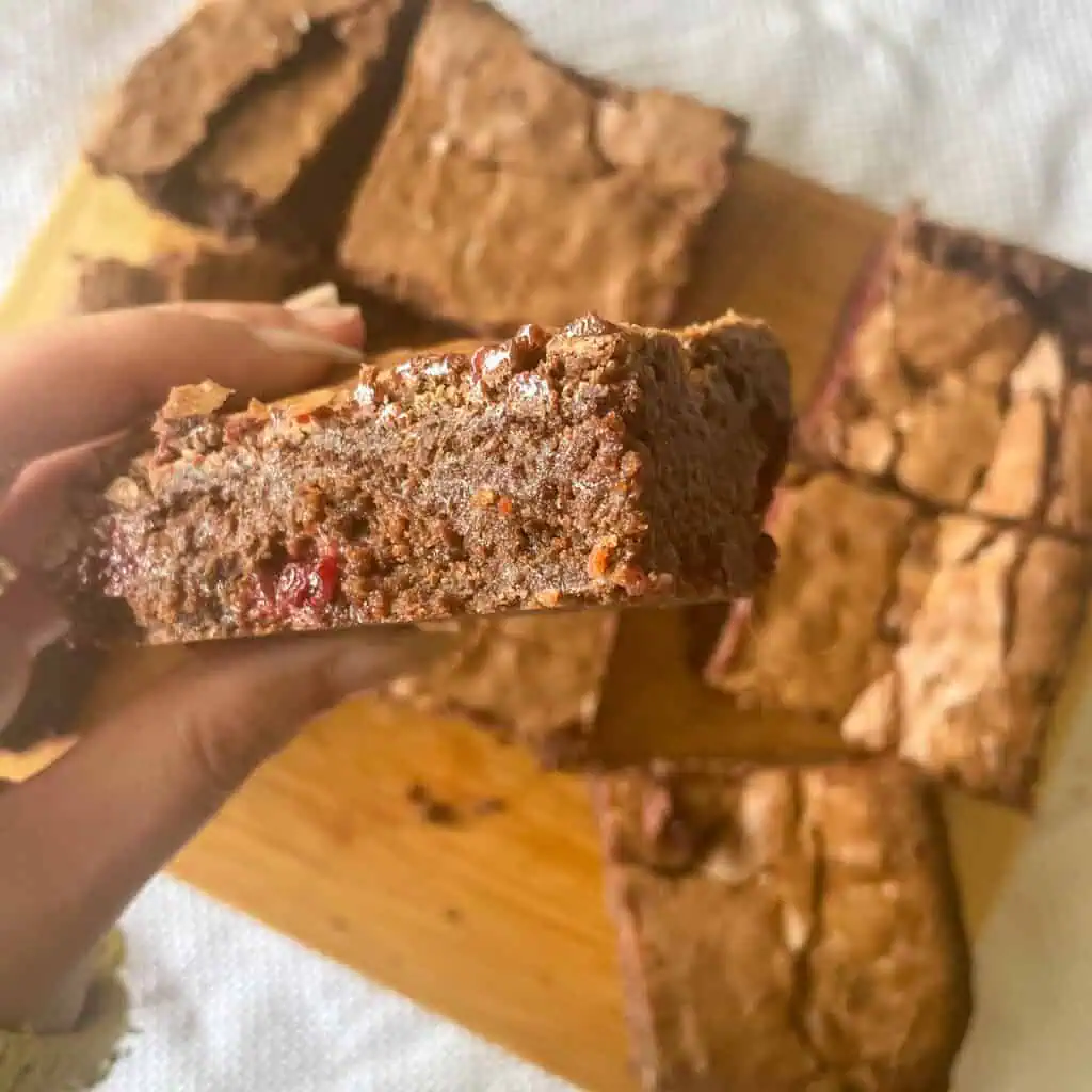 a hand holding a chocolate and blackberry brownie