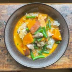 overhead shot of chicken and butternut squash curry in a black bowl