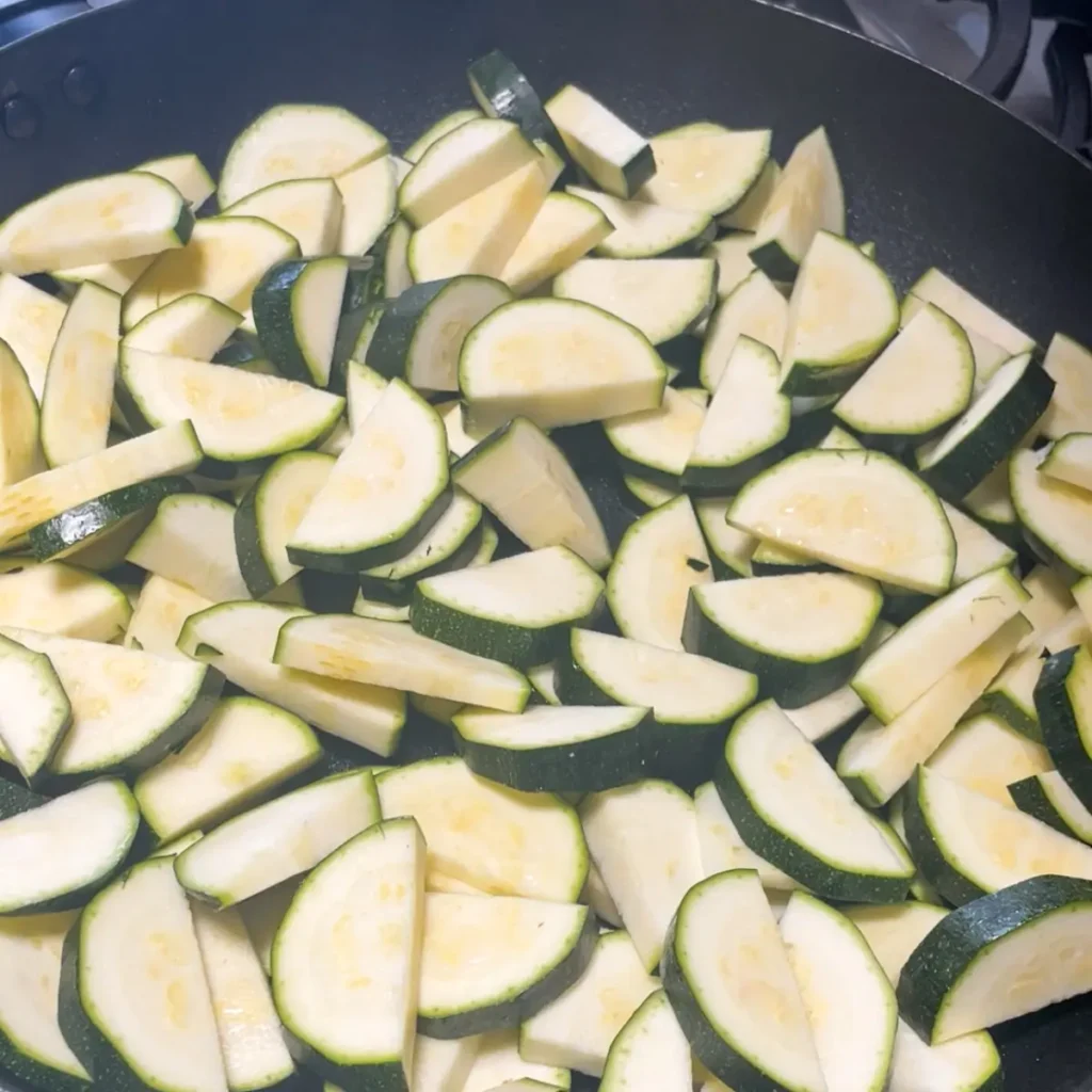 Sliced courgettes in a pan about to be cooked