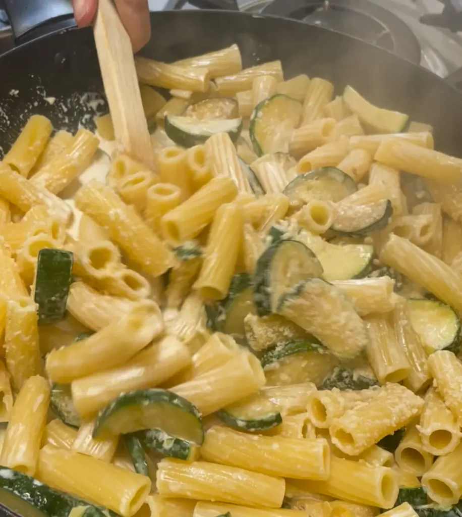 Pasta and Parmesan being added to creamy courgette sauce