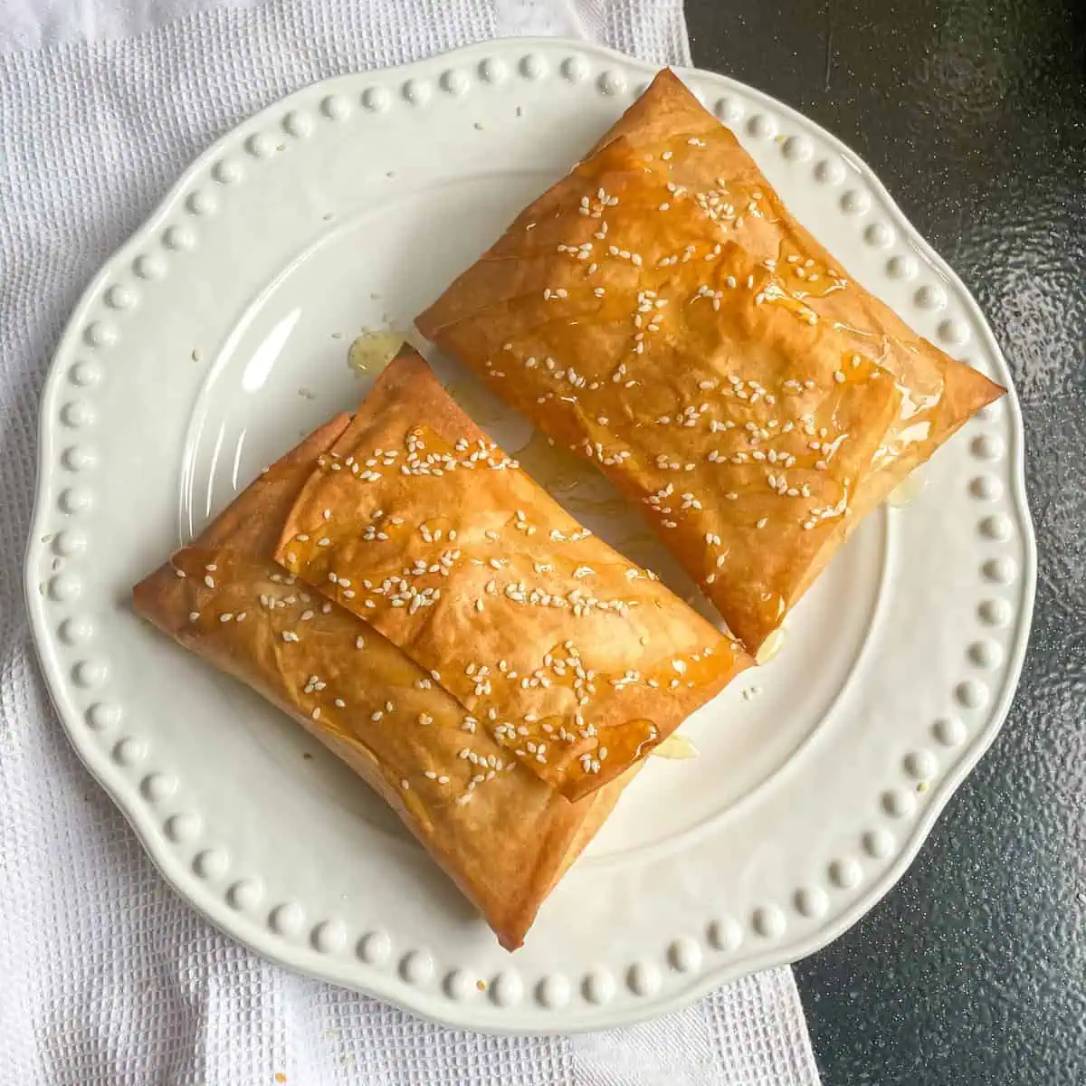 Two Feta olive and chilli filo parcels on a white plate