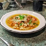 Pancetta mushroom and spelt broth In a white bowl on a kitchen work surface