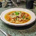 Pancetta mushroom and spelt broth In a white bowl on a kitchen work surface
