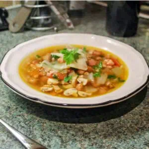 Pancetta mushroom and spelt broth In a white bowl on a kitchen work surface
