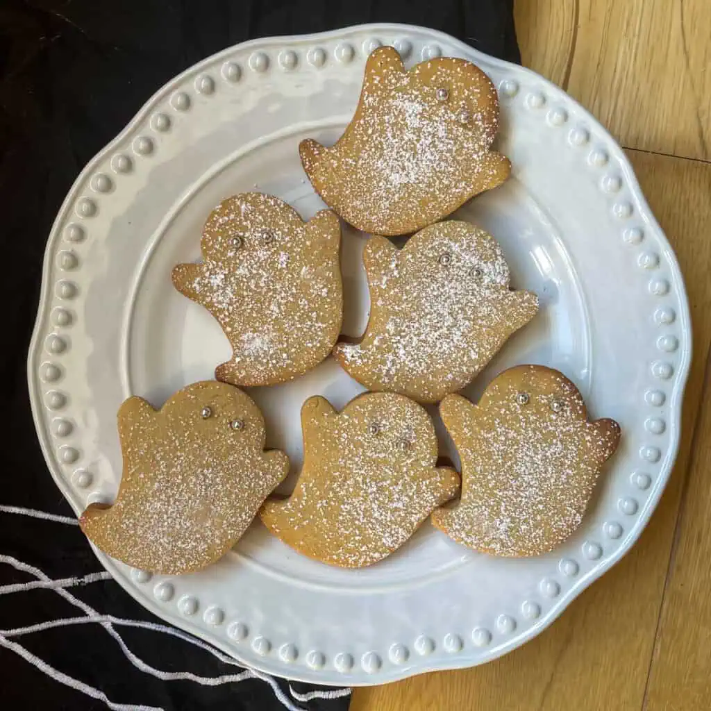 Ghost-shaped Halloween biscuits with jam filling and silver ball eyes