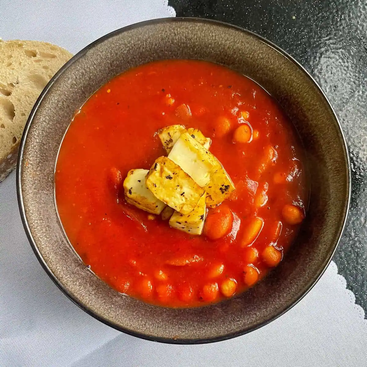 Butter bean and halloumi stew with pesto Top view with sourdough on the side