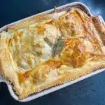 overhead shot of coq au vin pie topped with puff pastry and a sprig of thyme