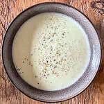 Leek and potato soup on a wooden table in a black bowl