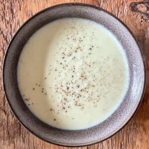 Leek and potato soup on a wooden table in a black bowl