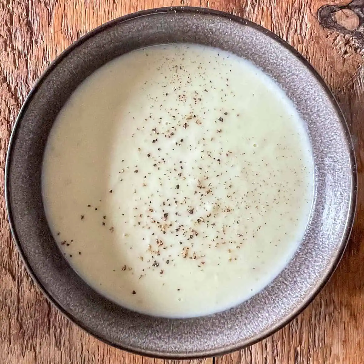 Leek and potato soup on a wooden table in a black bowl