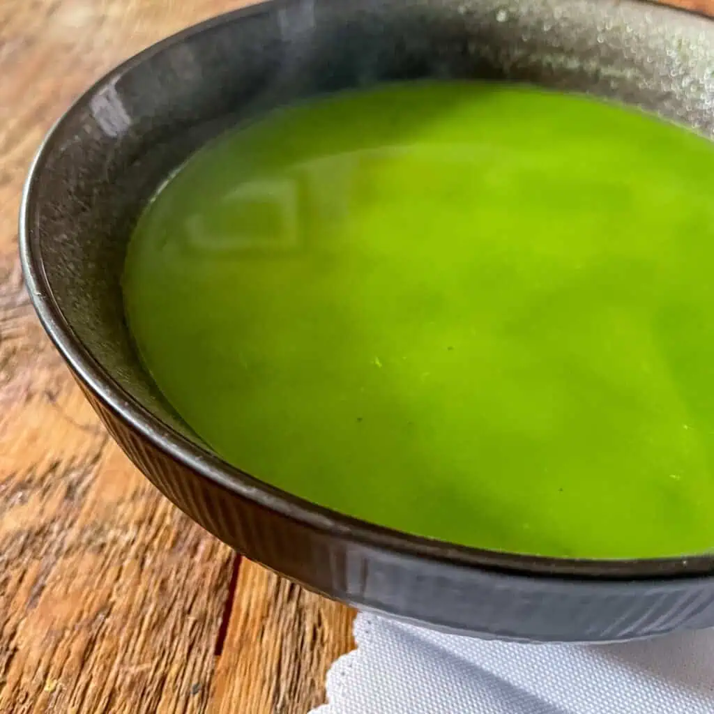 A black bowl with bright green watercress soup in it