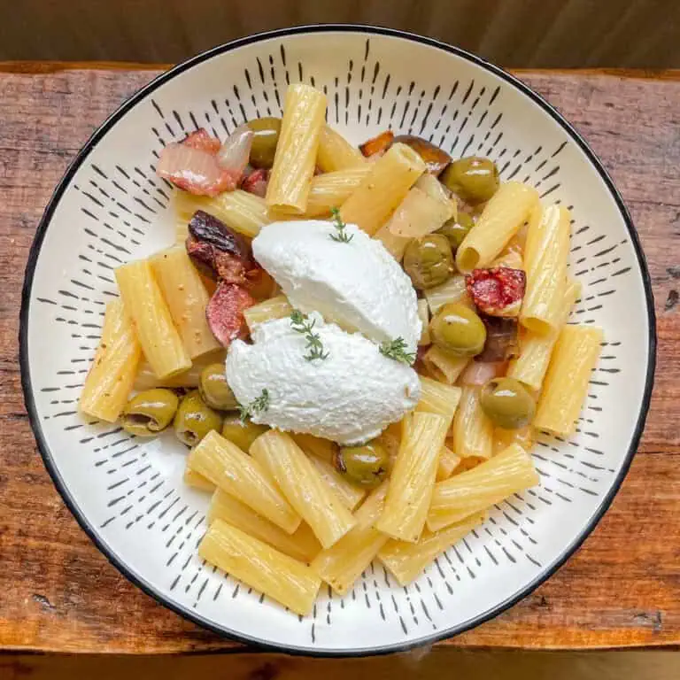 Vegetarian Christmas pasta with figs green olives and ricotta in a white bowl on a wooden table