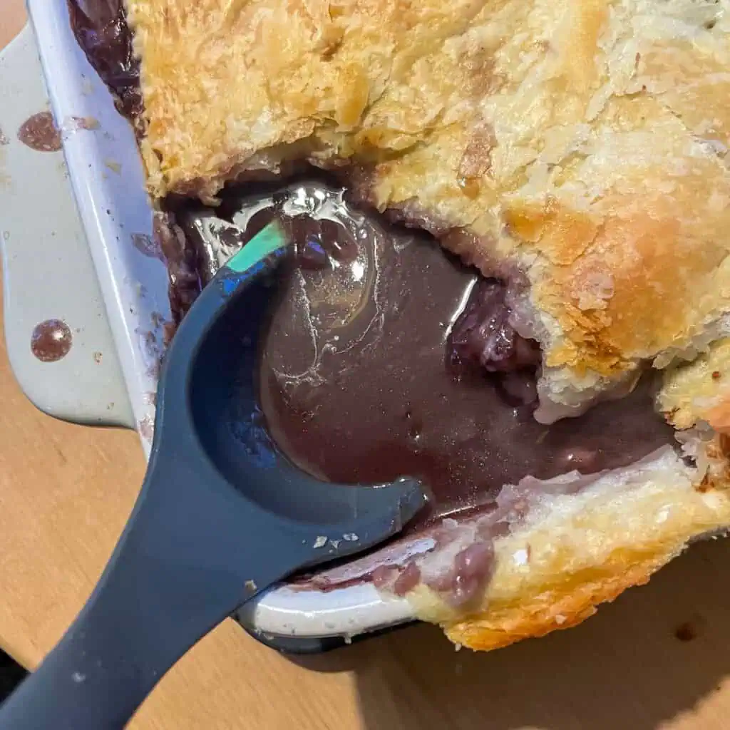 Coq au vin pie with a ladle in it ready to be served