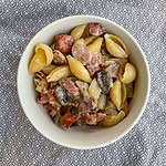 Bacon and mushroom pasta In a white bowl on a grey tablecloth