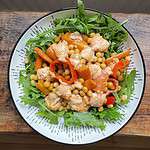 Warm roasted chickpea salad With dressing in a white bowl on a wooden table