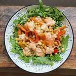 Warm roasted chickpea salad With dressing in a white bowl on a wooden table