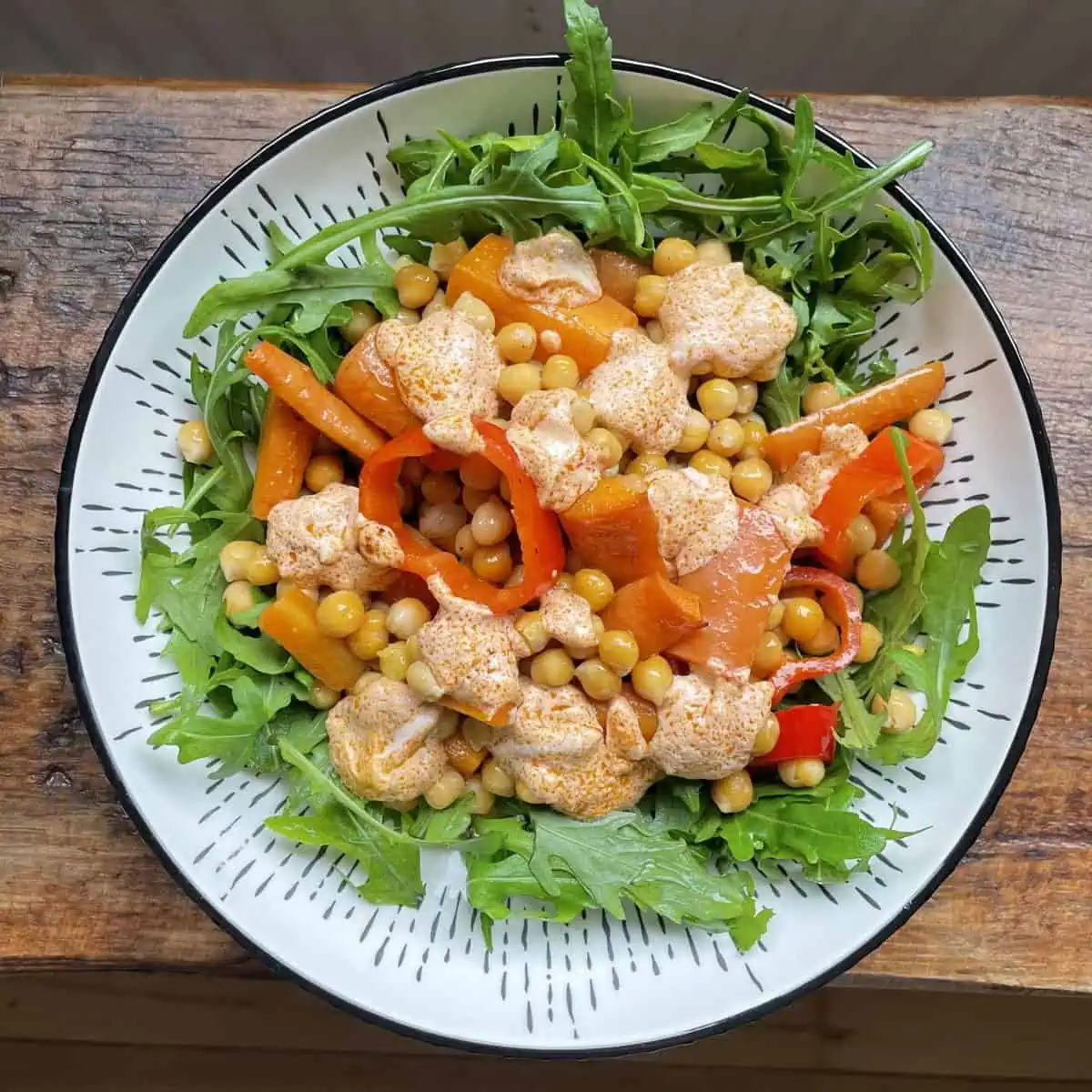 Warm roasted chickpea salad With dressing in a white bowl on a wooden table