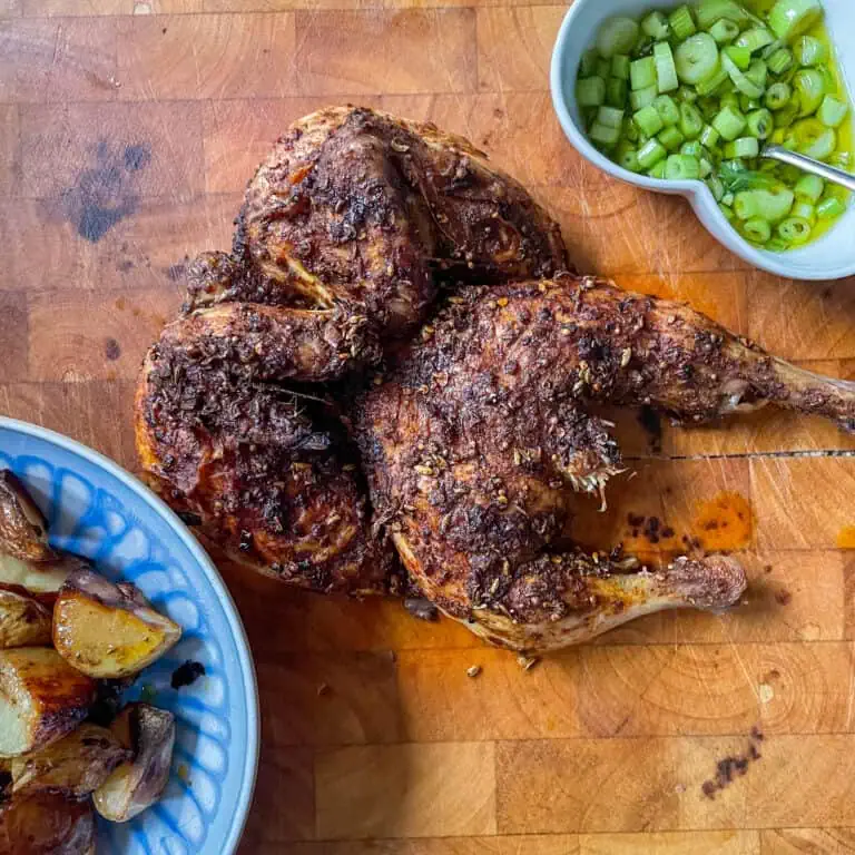 Persian roast spatchcock chicken On a wooden board with potatoes and spring onions