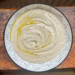 overhead view of white bean hummus in a bowl topped with olive oil