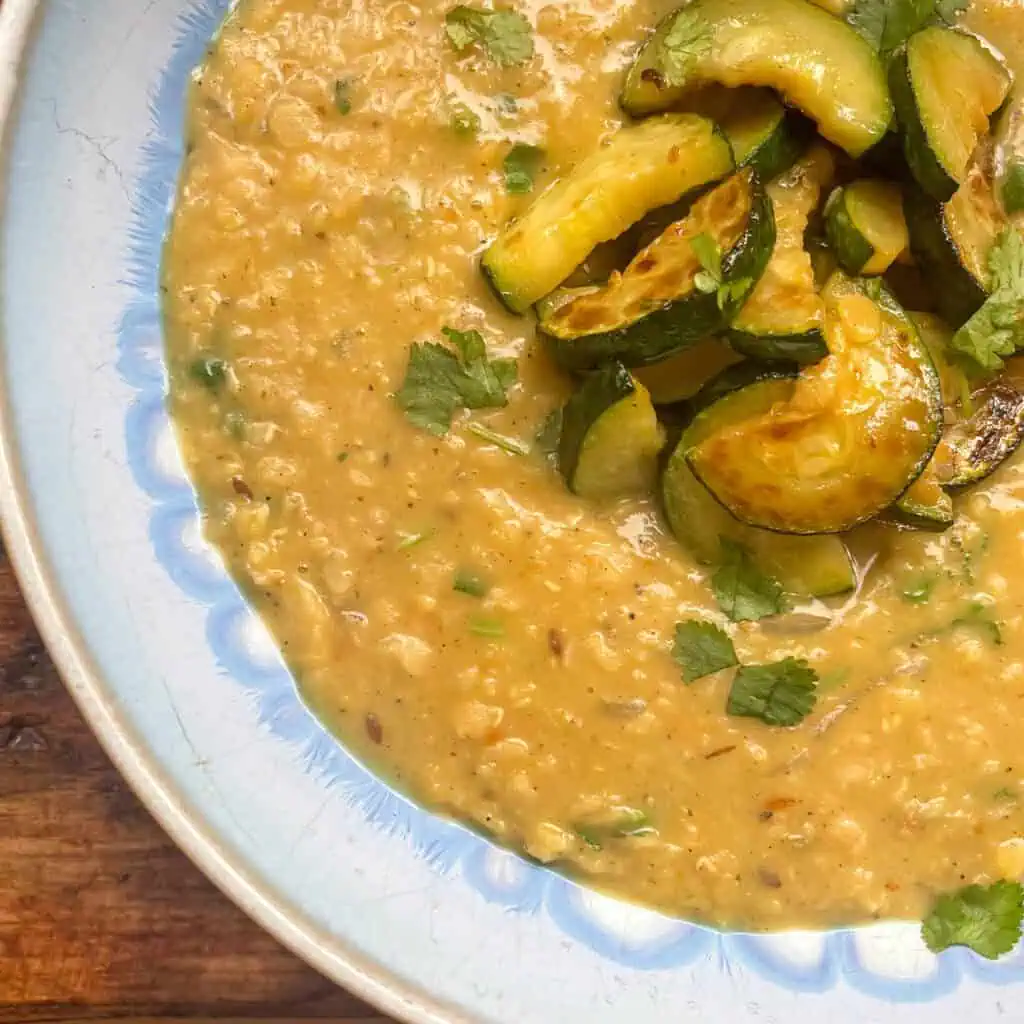 Close up of courgette and coconut dal in a blue bowl