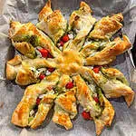 Homemade baked Christmas puff pastry snowflake with halloumi and pesto