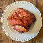 whole baked ham cooked in ginger beer on a white plate