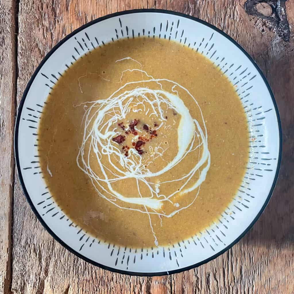 Easy 5 ingredient leek and chorizo soup in a white bowl on a wooden table