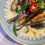 Fresh Thai mussels in creamy coconut broth with vibrant samphire garnish