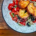Golden roasted halloumi on top of pearl couscous with roasted red peppers and black olives